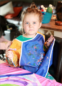 Young child painting with bright colours